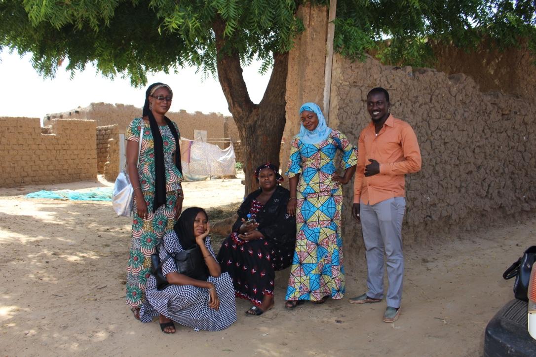 PMA 3 Five women on a dirt road with trees and buildings